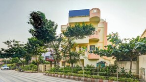 A multi-story hotel with balconies, a paved walkway, and greenery. - DhamStay Hotel Moon Near Niladri Beach (Puri)