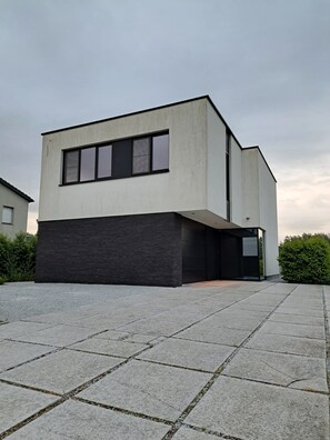 Un bâtiment moderne doté d’un toit plat, de grandes fenêtres et d’une façade sombre.