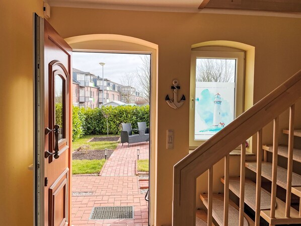 A staircase leading to a landing with a view of a garden and a building in the background.