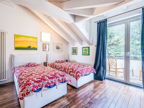 Ein Schlafzimmer mit zwei Betten, Holzböden, einem großen Fenster mit Blick und Kunstwerken an den Wänden.