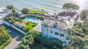 Vista aérea de una zona residencial con piscina, paneles solares y vistas al océano.