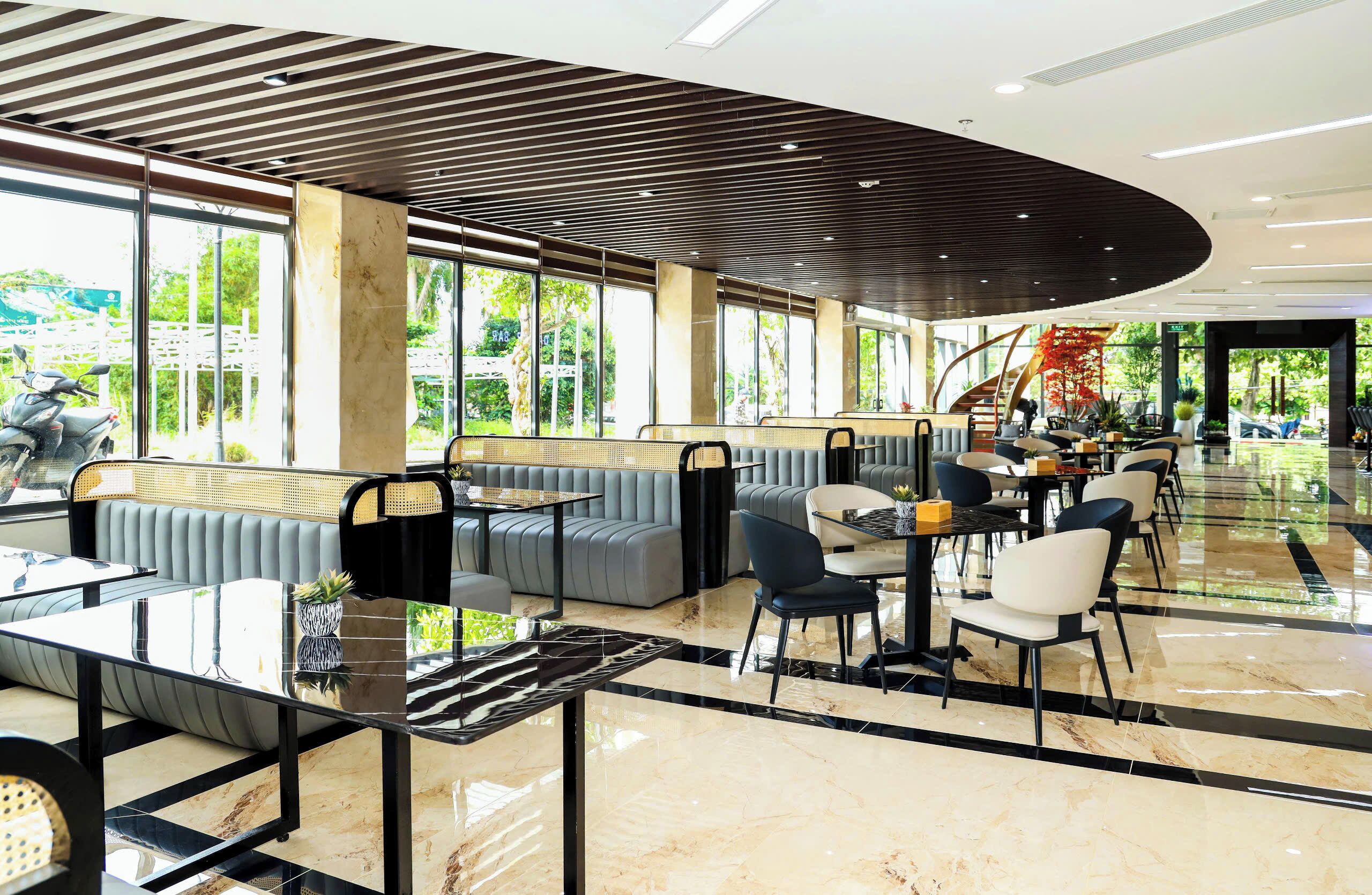A modern indoor space with seating areas, tables, and large windows offering views of the outdoors.