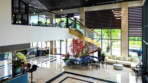 Un vestíbulo espacioso con una escalera moderna, zonas de estar y ventanas amplias que ofrecen vistas al verdor.