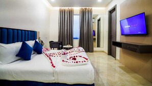 Habitación de hotel con cama, televisión, escritorio y vista al mar.
