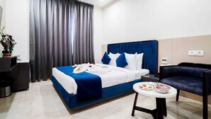 Una habitación de hotel con una cama grande, una mesa pequeña con comida, una silla y un televisor.