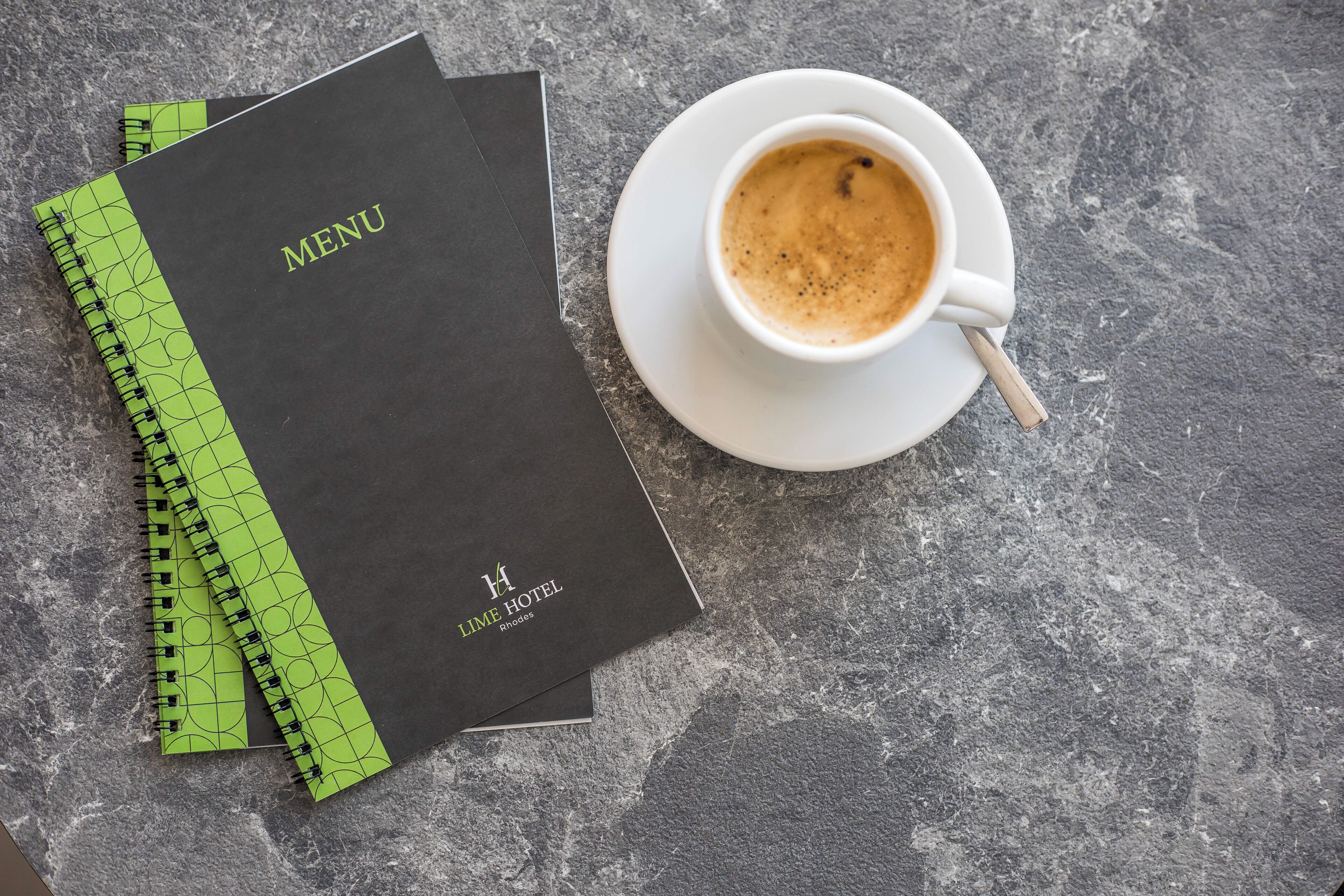 A menu booklet and a cup of coffee on a textured surface.
