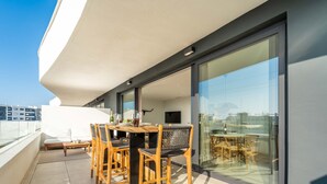 A modern balcony with a wooden table and chairs, a sofa, and a glass partition. - Casa Lozano - Sea View Apartment with Terrace and Pool, Higueron West, Fuengirola (Fuengirola)