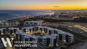 A high-rise residential building complex with multiple balconies and a central courtyard, overlooking a coastal cityscape during sunset. - Casa Lozano - Sea View Apartment with Terrace and Pool, Higueron West, Fuengirola (Fuengirola)