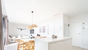 A bright, modern kitchen with a large island, wooden chairs, and a pendant light. - Casa Lozano - Sea View Apartment with Terrace and Pool, Higueron West, Fuengirola (Fuengirola)