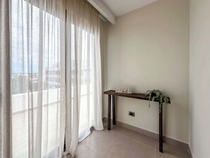 A room with sheer white curtains, a wooden console table with a 'LOVE' sign, and a view of buildings through the window. - 4 Bedroom Beach Penthouse w private rooftop (Punta Cana)