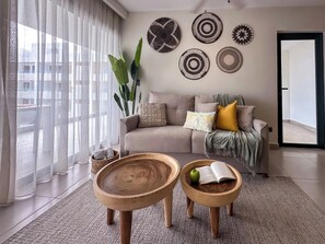 A modern living room with a sofa, two wooden side tables, and decorative wall art. - 4 Bedroom Beach Penthouse w private rooftop (Punta Cana)