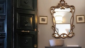 A room with a dark wooden door, a grey dresser, and a decorative mirror above it.