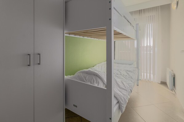 A bedroom with a bunk bed, a wardrobe, and a radiator.