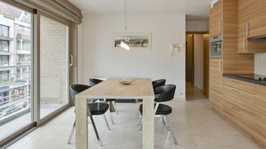 Eine moderne Küche mit einem Holzespeisetisch, schwarzen Stühlen und einer Pendelleuchte.