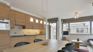 Eine moderne Küche mit Holzschränken, einem Esstisch und einem Fernseher.
