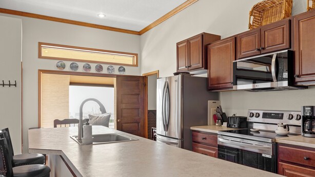 A modern kitchen with a large island, stainless steel appliances, wooden cabinets, and a view to the dining area.