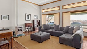 A living room with a sectional sofa, ottoman, and a wood-burning stove.