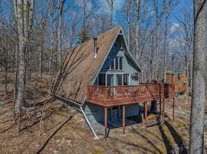 Een chalet met een schuin dak, een balkon en een schoorsteen.