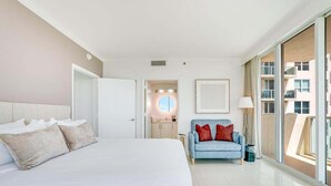 A modern hotel room with a large bed, a sofa, and a view through a sliding door.