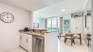 A modern kitchen with a built-in dishwasher, a coffee maker, and a large window offering a view.