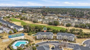 Zona residencial com campo de golfe, piscina e um grande conjunto de edifícios.