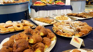 A buffet with various baked goods including croissants, pastries, and waffles.