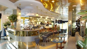 A modern bar area with a curved counter, bar stools, and a bartender.