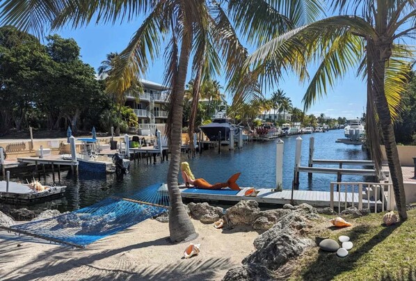 A marina with boats docked, a hammock on the sand, and palm trees. - Port Largo Villas Escape 5A (Key Largo)