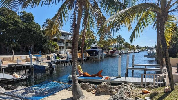 A marina with boats docked, a hammock on the sand, and palm trees. - Port Largo Villas Escape 5A (Key Largo)