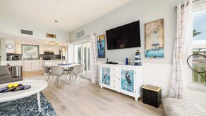 A modern living room with a dining area, a kitchen, and a TV mounted on the wall. - Port Largo Villas Escape 5A (Key Largo)