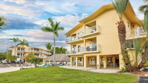 A multi-story hotel with balconies, a pool area, and palm trees.