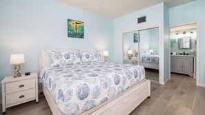 A bedroom with a bed, nightstands, a dresser, a mirror, and a painting on the wall.
