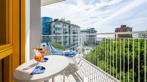 Un balcon avec une table, deux verres de vin et une vue sur une piscine et des immeubles.