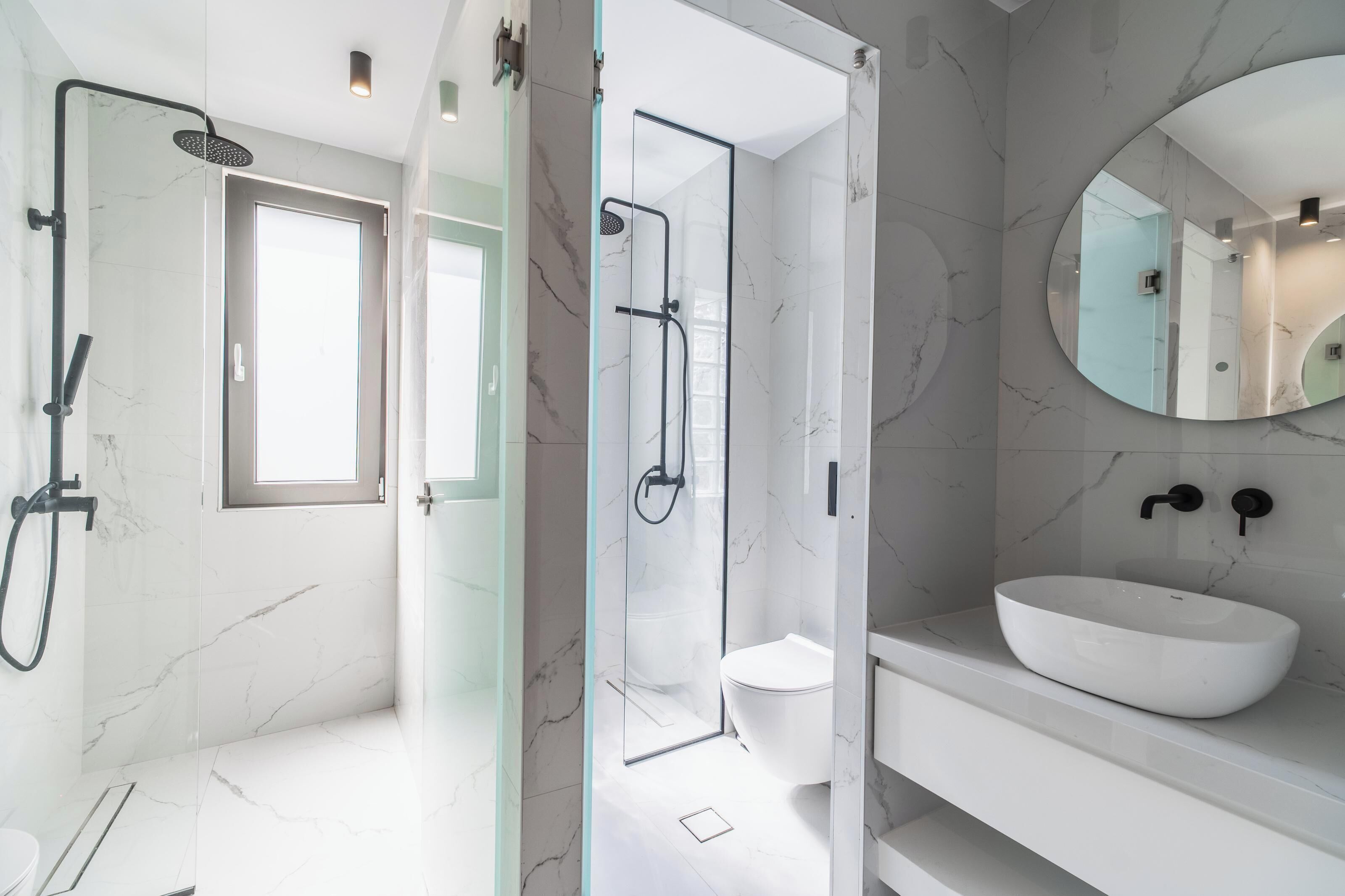 A modern bathroom with a glass-enclosed shower, a white sink, and a large mirror.