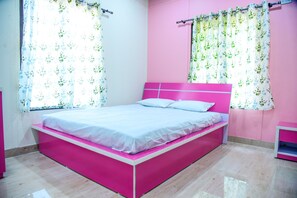 A pink and white bed in a room with floral curtains and a pink wall.