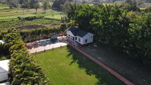 A house with a swimming pool, surrounded by lush greenery and a hilly landscape.