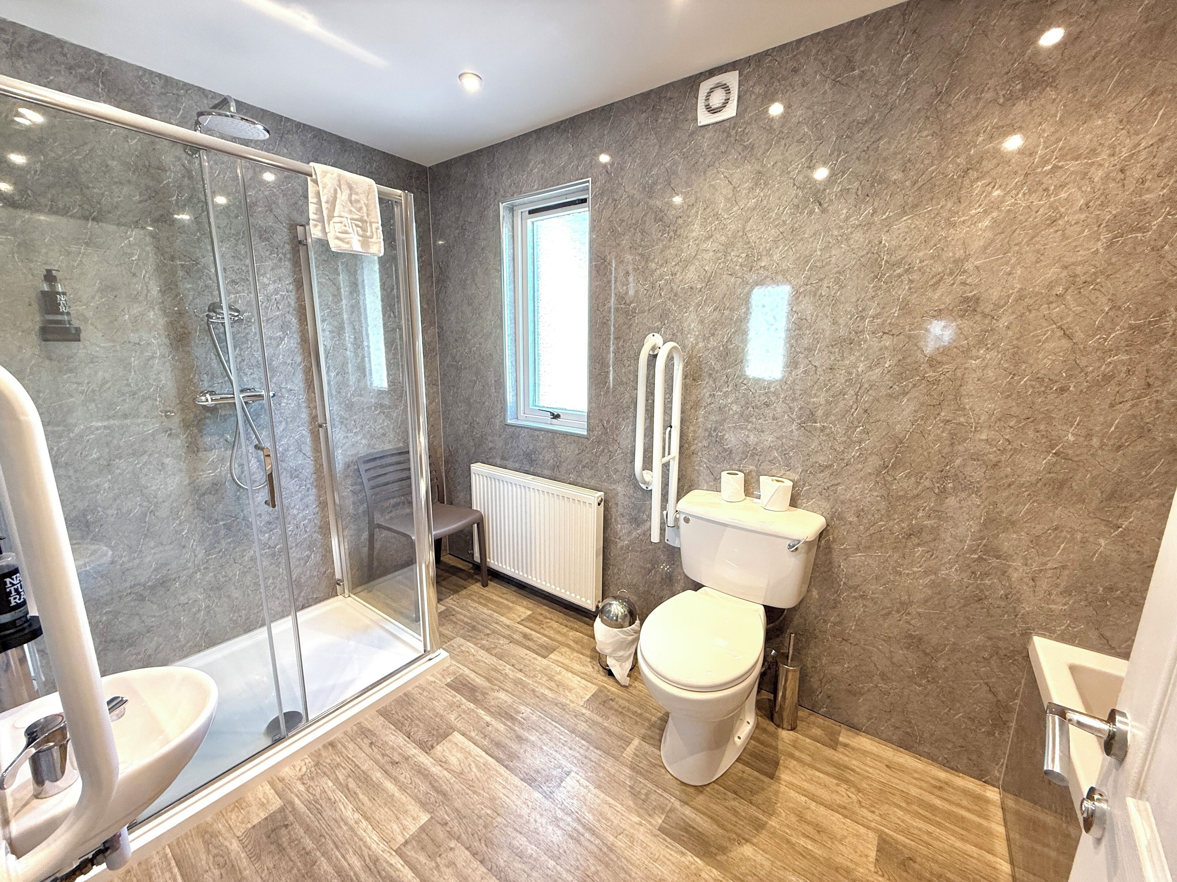 A modern bathroom with a glass shower enclosure, a toilet, and a sink.