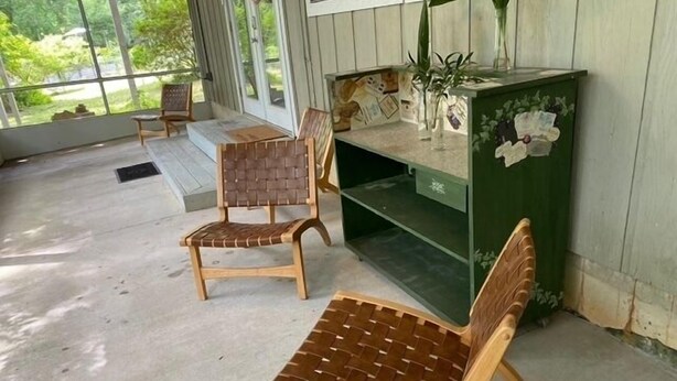 A covered porch with two wicker chairs and a green cabinet with decorative items. - Quiet Retreat for longer term bookings- Downstairs apartment 5 miles to FSU (Tallahassee)