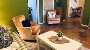A living room with a checkered sofa, a beige armchair, a white coffee table with a plant, and a Florida-themed pillow on a chair. - Quiet Retreat for longer term bookings- Downstairs apartment 5 miles to FSU (Tallahassee)