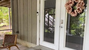 A porch with a wooden bench, a door with a wreath, and a doormat. - Quiet Retreat for longer term bookings- Downstairs apartment 5 miles to FSU (Tallahassee)