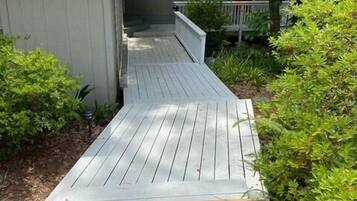 Une terrasse en bois menant à une maison dotée d’un porche abrité.
