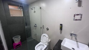 A modern bathroom with a glass-enclosed shower, a white toilet, and a sink with a marble countertop. - Hotel Anupam (Mahabaleshwar)