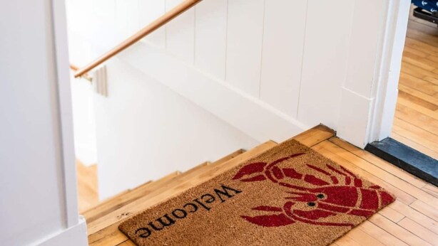 Een houten vloer met een vloermat bij de ingang.