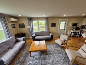 Un salon comprenant un canapé, des fauteuils, une table basse et donnant sur l’extérieur.