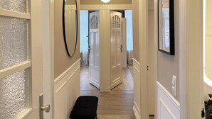 A hallway with a bench, a round mirror, and a ceiling light fixture.