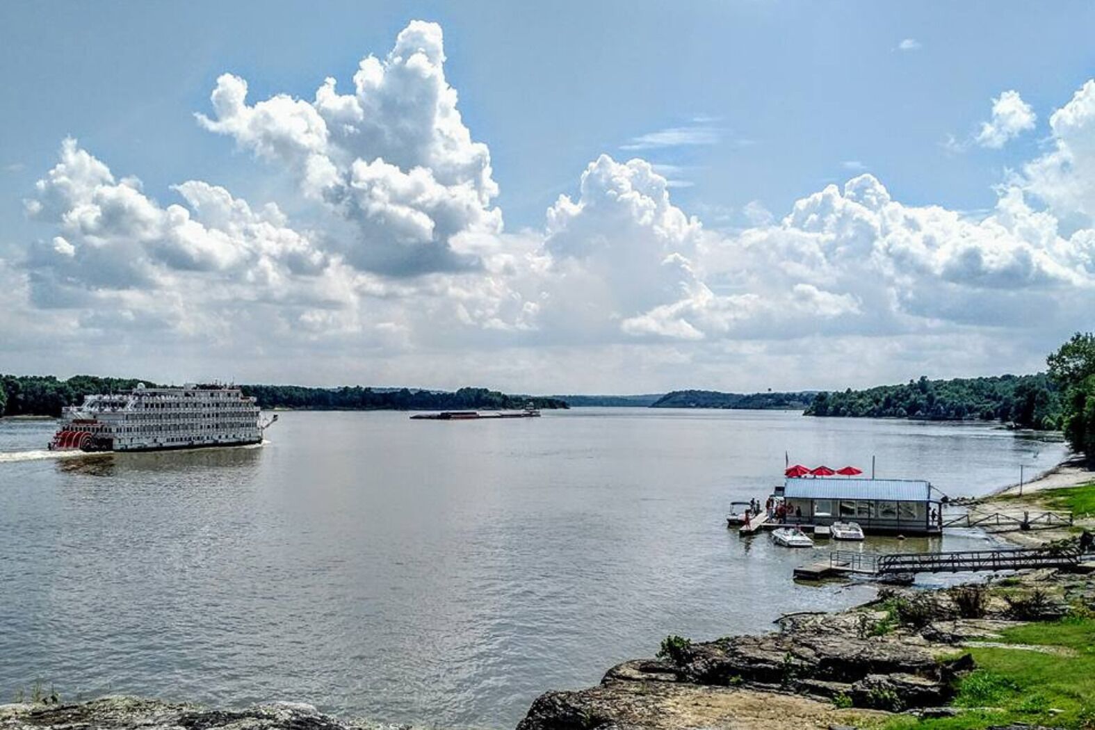 Ein Fluss mit einem großen Kreuzfahrtschiff und einem vertäuten Boot.