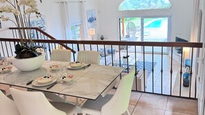 A dining area with a marble table, white chairs, and a hanging light fixture. - VILLA PALM BEACH sea front  (cannes)