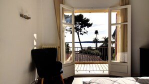 A bedroom with a large window, a bed, and a chair. - VILLA PALM BEACH sea front  (cannes)