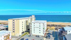A multi-story hotel with a parking lot and a view of the beach. - Modern and remodeled 1BD and 1.5 Bath direct Ocean Front condo with Free WiFi and linens included (Ocean City)