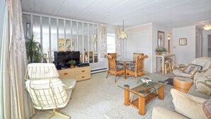 A living room with a TV, a dining table with chairs, a sofa, and a coffee table. - Modern and remodeled 1BD and 1.5 Bath direct Ocean Front condo with Free WiFi and linens included (Ocean City)